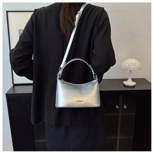 Detail of a silver metallic crossbody bag showing sleek leather texture and logo