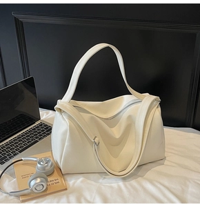Detailed macro view of cream pebbled leather texture and dual straps on large tote bag