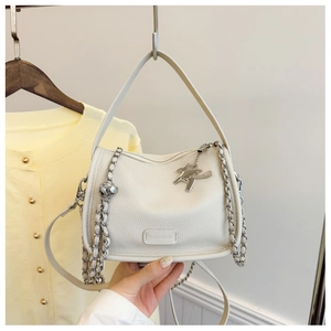 Macro shot of white pebble grain leather handbag with silver pegasus charm and chain detail