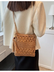Sac à bandoulière en paille marron évidé avec tissage floral et gland sur modèle