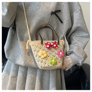 Detail showing hand-woven texture with 3D crochet flowers and polka dot bow on the bucket bag