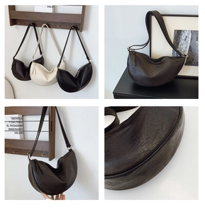 Close-up of minimalist crescent crossbody bag with wrinkled leather and metal hardware