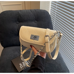 Detail of beige quilted glossy handbag with silver chain and square metal turn-lock