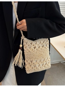 Sac bandoulière beige en paille tressée avec motifs ajourés et pompon décoratif