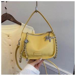Detailed close-up of yellow pebble leather square bag with silver horse charm and chain strap