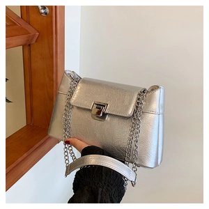 Détail du sac argenté texture crocodile avec bandoulière chaîne et fermoir métallique