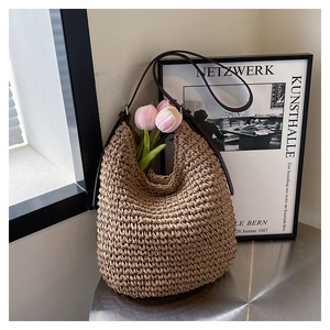Détail du sac seau en paille tressée kaki avec bandoulière en cuir marron foncé robuste