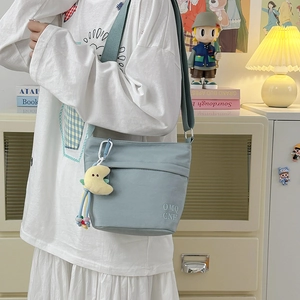 Dettaglio borsa a secchiello in nylon azzurro con tracolla e ciondolo a luna in peluche