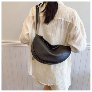 Detail of minimalist black crescent crossbody bag with adjustable silver buckle strap