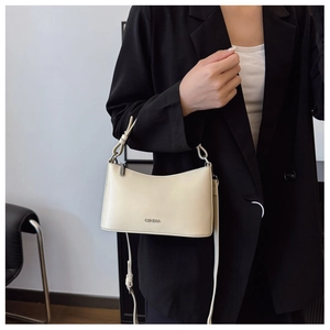 Detailed view of the CBNEKA metal logo on a cream dumpling-shaped commute shoulder bag