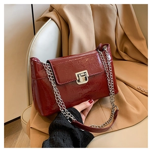 Détail du sac à main en cuir bordeaux texturé avec chaîne et fermoir rotatif