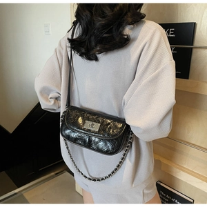 Fashionable black glossy pleated chain bag with silver buckle shown on a female model back view