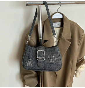 Detail of grey denim shoulder bag with silver star rivets and metal buckle hardware