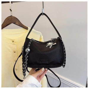 Close-up of black leather crossbody bag with lychee texture and silver chain strap