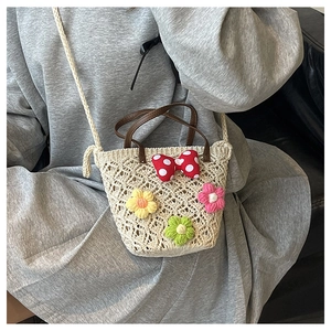 Detail of hand-woven cream bucket bag with crochet flowers and polka dot bow