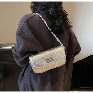 Detail of silver quilted leather crossbody bag with metal chain strap and twist lock closure