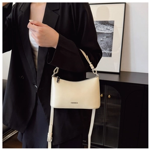 Detailed view of cream white crescent shoulder bag with metallic logo on premium leather