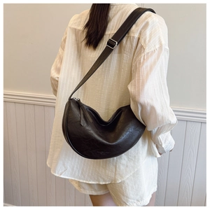 Detailed back view of a black crescent moon shoulder bag worn by a model in casual style