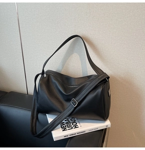 Detail of black lychee grain leather Boston bag with adjustable strap and silver hardware