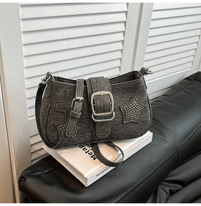 Detail of grey denim shoulder bag with silver star rivets and cross accents