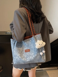 Large floral tote bag with woven brown handles and a cloud charm shown on shoulder