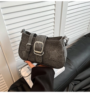 Detail of grey denim shoulder bag with silver star rivets and large metal buckle