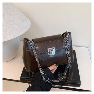 Détail du sac marron foncé effet crocodile avec boucle argentée sur des livres