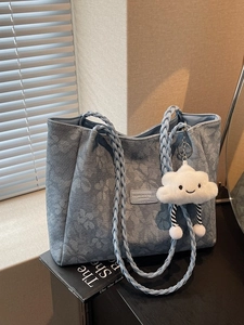 Blue floral jacquard tote bag with braided leather handles and plush cloud charm pendant