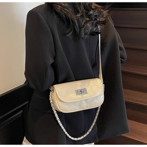 Rear view of cream quilted chain bag with silver twist lock on a black blazer