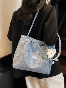 Blue floral tote bag with woven shoulder strap and cute cloud charm on model