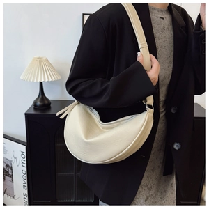 Detail view of cream-colored half moon crossbody bag with smooth faux leather texture