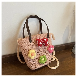 Detail of pink hand-crocheted bucket bag with floral accents and a red polka dot bow