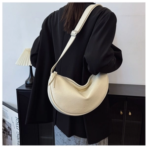 Detailed view of cream-colored crescent bag with textured leather and brand logo