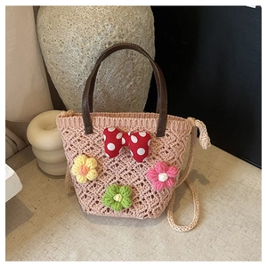 Detail of pink hand-woven bucket bag featuring a polka dot bow and floral crochet accents