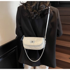 Detailed view of a white quilted mini flap bag with silver chain and metal turn-lock