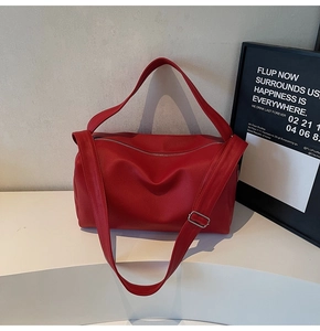 Detail of red pebbled leather shoulder bag showing the wide strap and silver metal buckle
