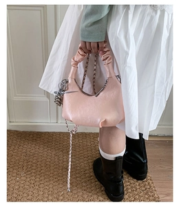 Close-up of pink crescent handbag featuring scrunchie handle and silver chain detail