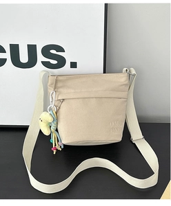 Dettaglio della borsa tote in nylon beige con ricamo OMQ CNH, cerniera e ciondoli carini