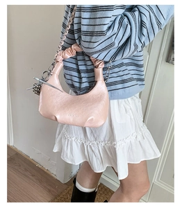 Detail of soft pink cloud bag featuring chic pleated handle and silver ball ornament