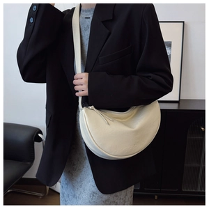 Model wearing a minimalist beige crescent bag with smooth matte synthetic leather texture