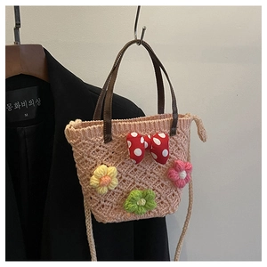 Close-up of hand-woven crochet bucket bag featuring 3D floral accents and a red polka dot bow