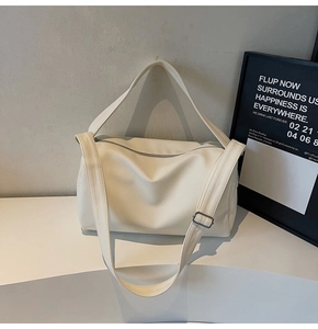 Detail view of large beige crossbody bag with lychee texture and wide shoulder strap