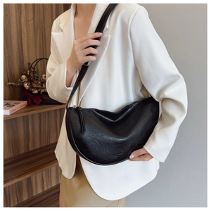 Minimalist black crescent leather crossbody bag styled on a white blazer outfit