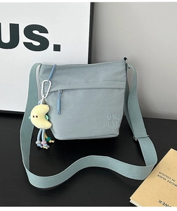 Dettaglio della borsa a tracolla in nylon verde menta con ricamo e ciondolo a luna