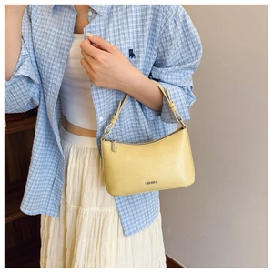 Close-up of pale yellow leather dumpling bag with metal zipper and knotted handle detail