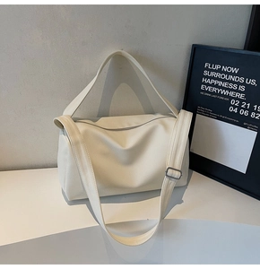 Detail of creamy white boston bag with pebble leather texture and adjustable strap