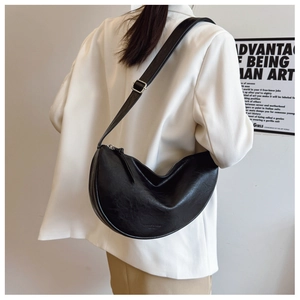 Detail view of black hobo bag with adjustable strap and brand logo on textured PU leather