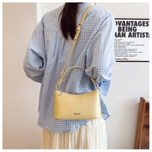 Pale yellow leather shoulder bag with zipper and adjustable strap shown on model