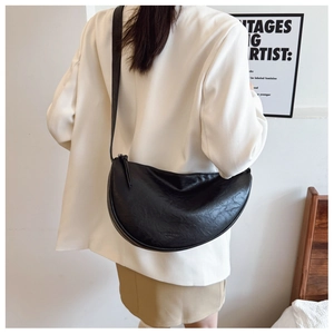 Detail of black crescent crossbody bag showing textured matte finish and gold branding