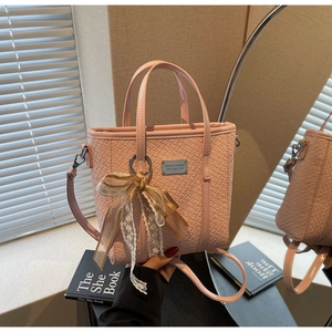 Dettaglio della borsa a secchiello rosa intrecciata con fiocco in pizzo beige e texture